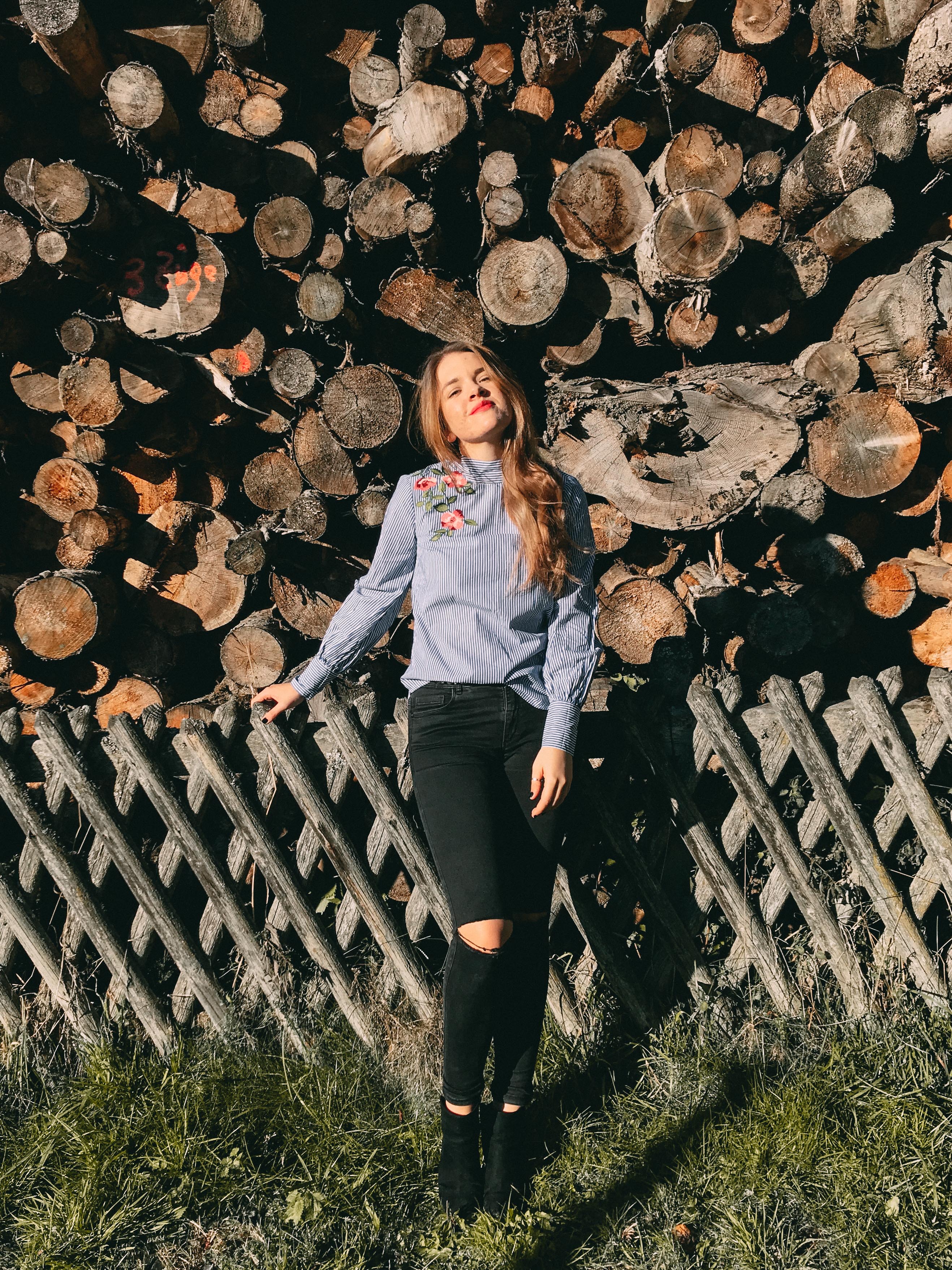 Bild von Saskia vor einem Holzstapel
